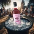 Flasche FICKEN Alkoholfrei im Eiskübel mit Eis, draußen bei Tageslicht, junge Leute feiern im Hintergrund.
